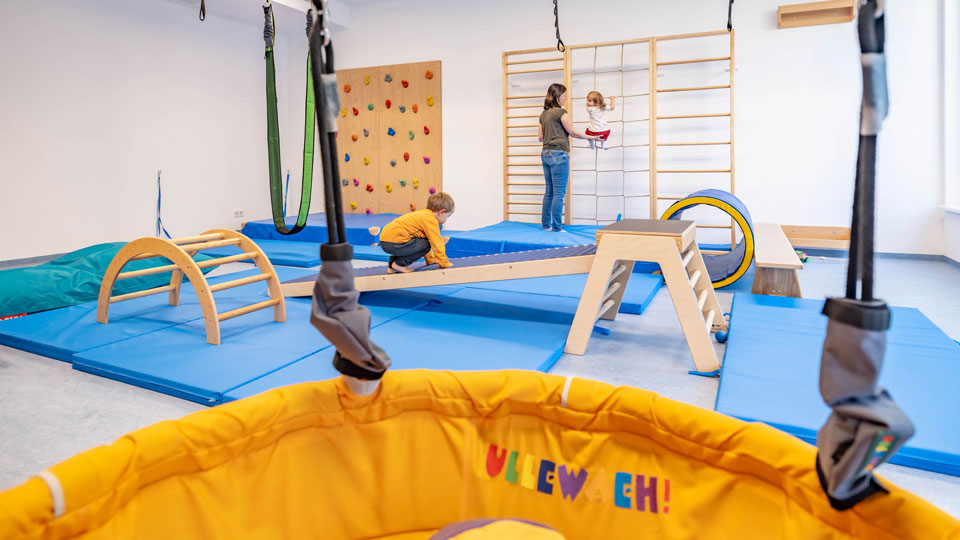 Großer Turnsaal mit Kletterwand und Rollrutsche in FABIs Kindernest