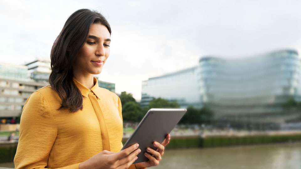 Frau mit Tablet an einem Flussufer