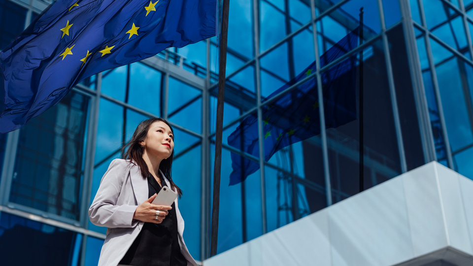 Frau vor Gebaeude mit EU-Flagge