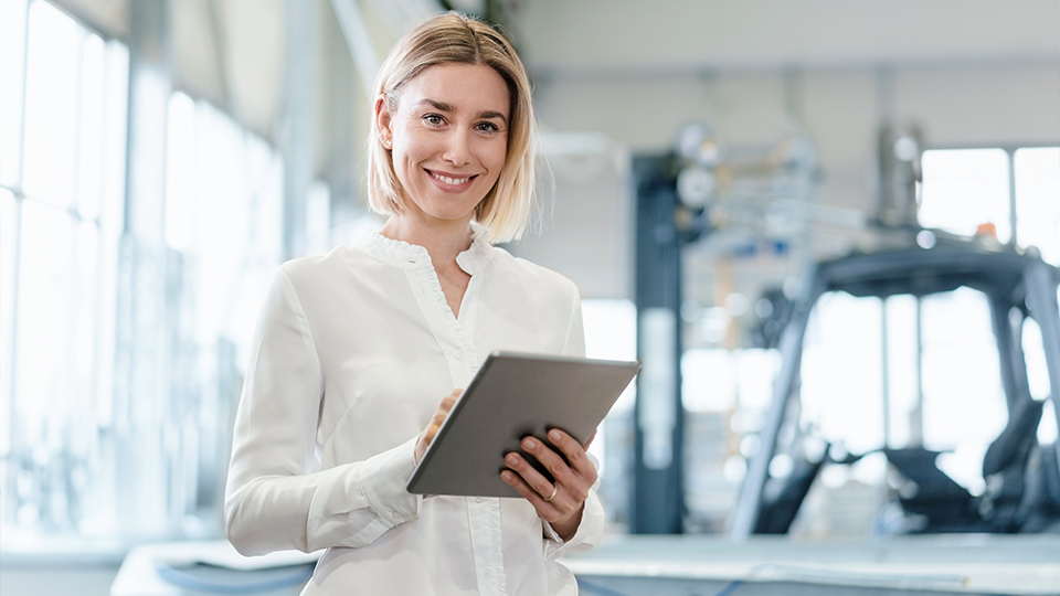 Woman in white shirt holds a tablet in her hand