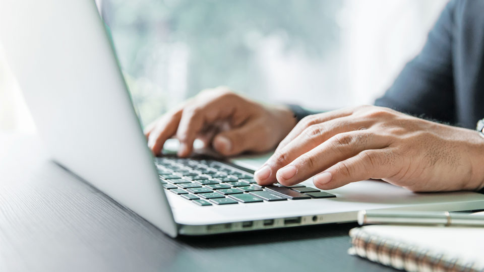 Close-up of the hands of a person typing on a laptop