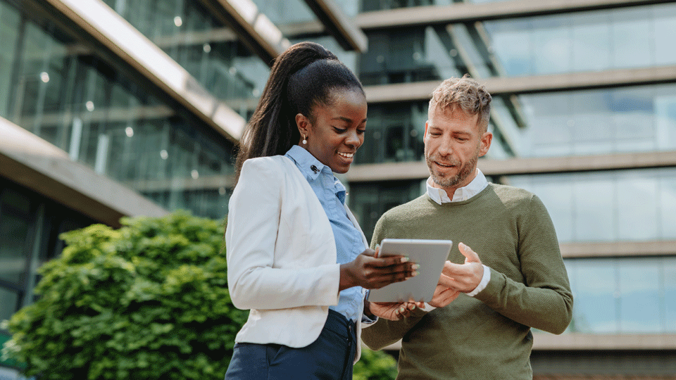 Two people standing in an office looking at a tablet