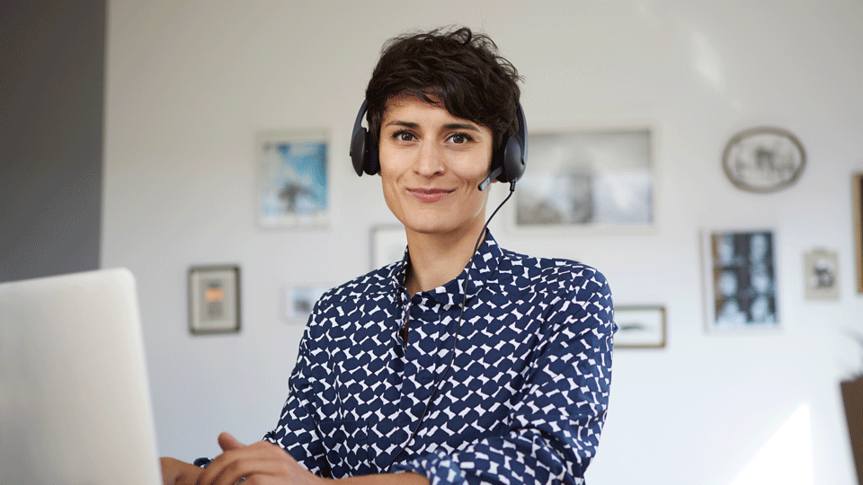 Woman wearing a headset sits in front of a laptop