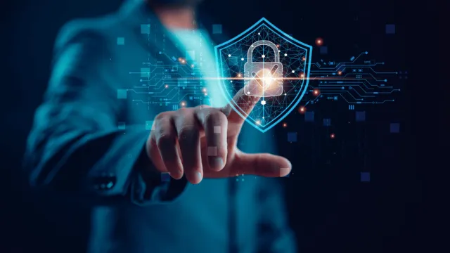 Person vor dunklem Hintergrund zeigt auf Cyber Security Symbol
